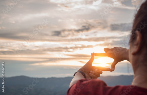 The woman making frame round the sun with her hands in sunrise,Future planning idea concept,copy space,warm retro tone.