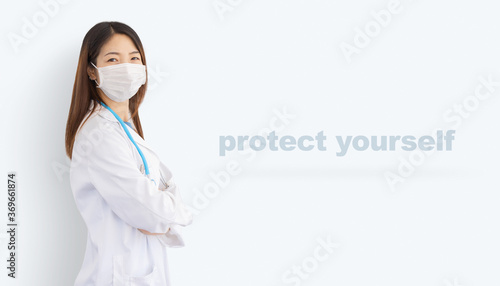 beautiful asian woman wearing white coat, protective mask and stethoscope isolated on background with "protect yourself" text, concept about safety measures and prevention of epidemic infection