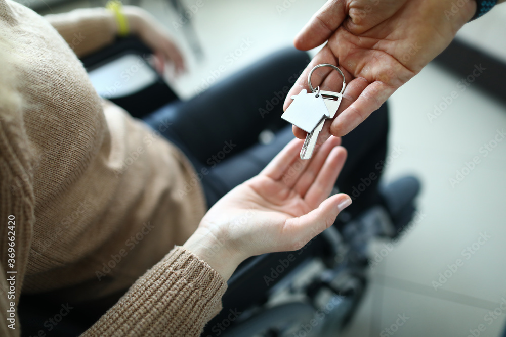 Obraz premium A woman in a wheelchair receives the keys to the house from the hands of a man. Active employment of people with disabilities