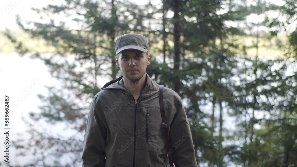 Portrait of Young Smiling Man Standing in Forest. Traveling Concept People in Nature. One Person Tourist Looking at Camera On the Background of Landscape Closeup. Hiker Journey in Wildlife Portrait of Young Smiling Man Standing in Forest. Traveling Concept People in Nature. One Person Tourist Looking at Camera On the Background of Landscape Closeup. Hiker Journey in Wildlife