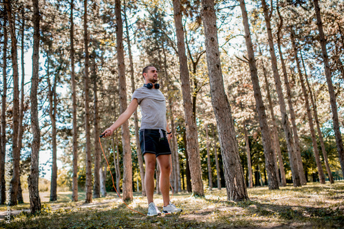 Fototapeta Naklejka Na Ścianę i Meble -  Young man exercising with jumping rope outdoors 