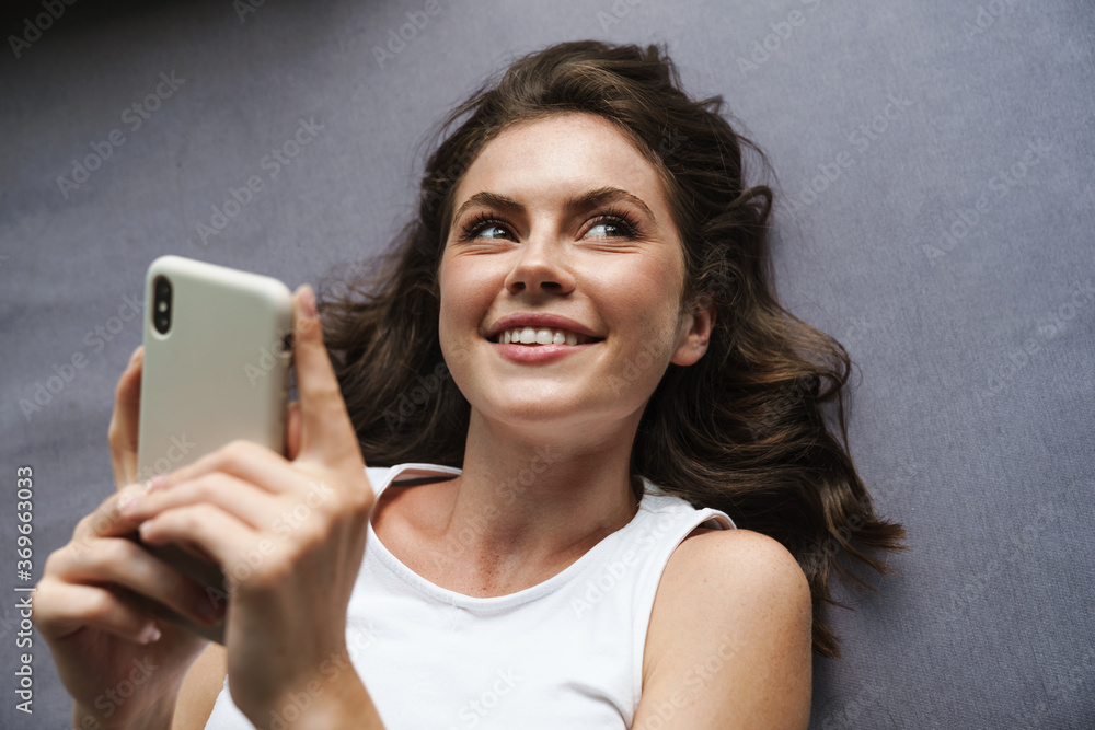 Image of beautiful cheerful woman smiling and using mobile phone Image of beautiful cheerful woman smiling and using mobile phone