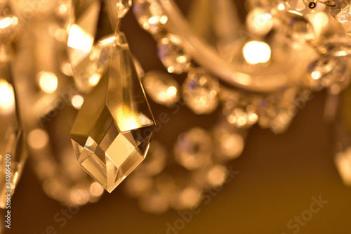 Crystal ornaments on antique chandelier. Warm white color balance. Vertical photo.