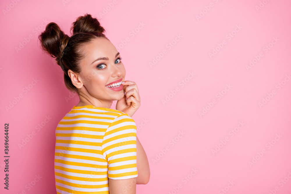 Closeup profile photo of attractive lady two funny buns hairdo beaming smile cheerful charming look flirty bite finger wear casual white yellow striped shirt isolated pink color background