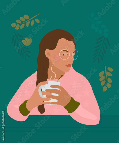Сute girl with braid holds cup with a hot drink in her hands.There is steam from a mug with tea, cacao or coffee.Cozy autumn mood.Young woman portrait with glasses and freckles. Pink casual sweatshirt