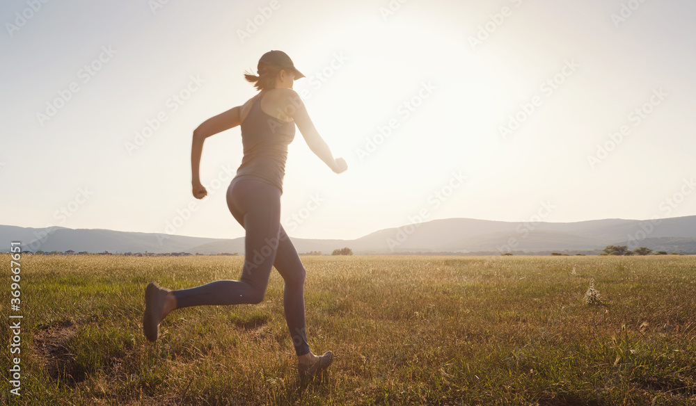 Jogging woman running in summer field at sunset Jogging woman running in summer field at sunset