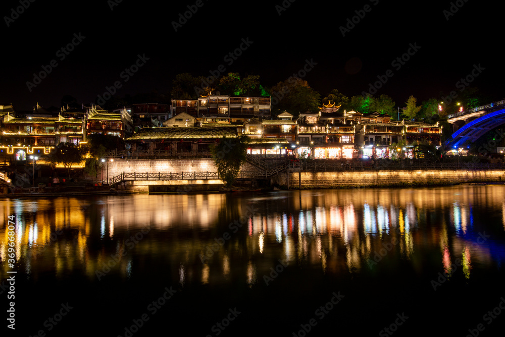 View of illuminated at night riverside houses in ancient town of Fenghuang known as Phoenix, China