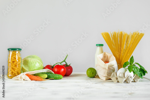 Front view of the different products in reusable packing on the bright wooden background . Concept of conscious choice of packaging