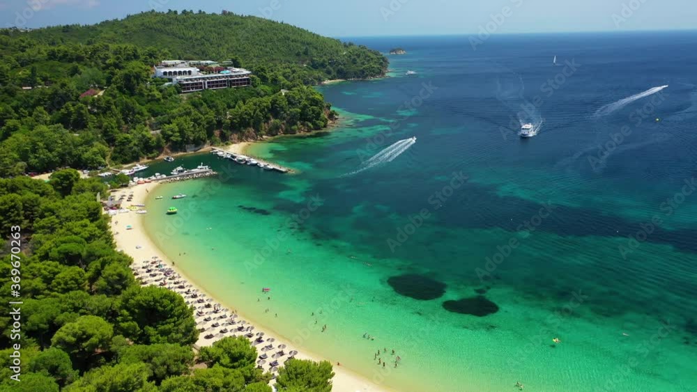 Aerial drone video of beautiful popular organised sandy bay, turquoise beach and natural preserve lake with pine trees of Koukounaries, Skiathos island, Sporades, Greece Aerial drone video of beautiful popular organised sandy bay, turquoise beach and natural preserve lake with pine trees of Koukounaries, Skiathos island, Sporades, Greece