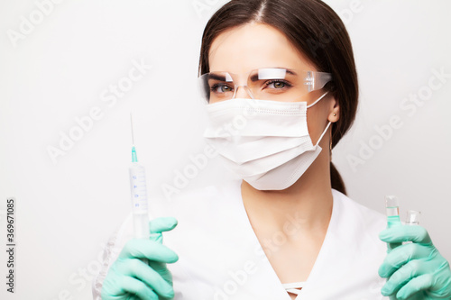 Woman doctor in medical mask picks up syringe to give an injection