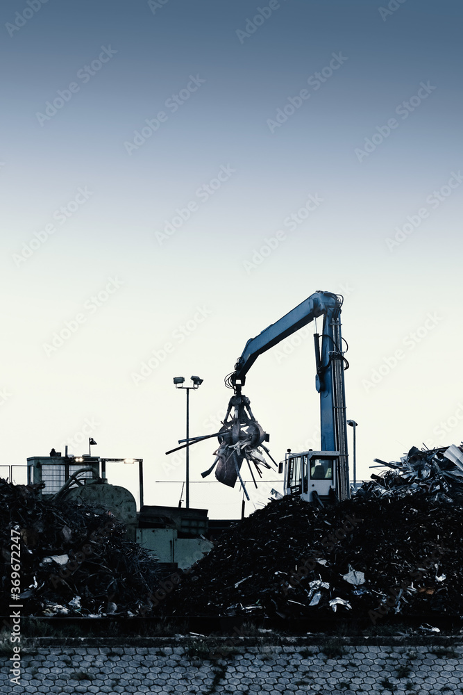 A crane loads metal scrap onto a recycling yard.