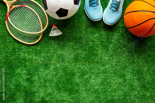 Sport balls and badminton rackets on football grass. Top view copy space © 9dreamstudio