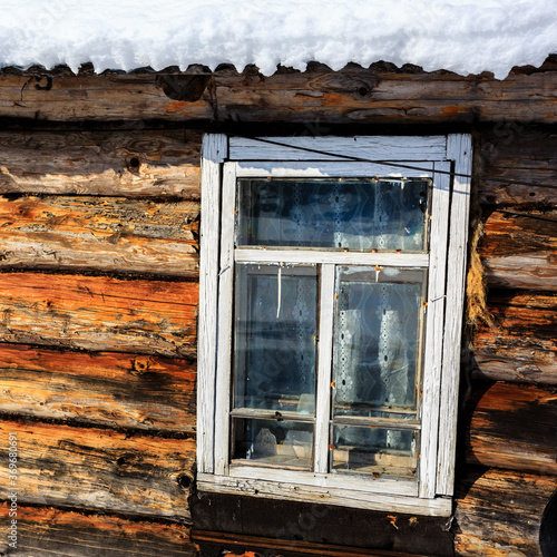 Old wooden window in winter  roof of the brown house covered with snow