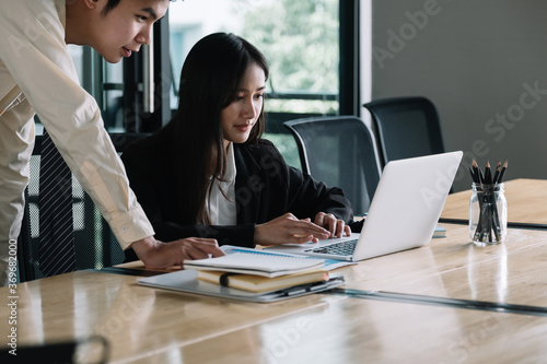 Asian business adviser meeting to analyze and discuss the situation with laptop computer in the meeting room. Investment Consultant