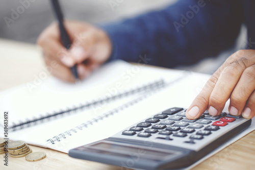 Close up young oman hand is writing in a notebook and using calculator counting making notes Accounting at doing finance at home office. Savings finances concept. note pad
