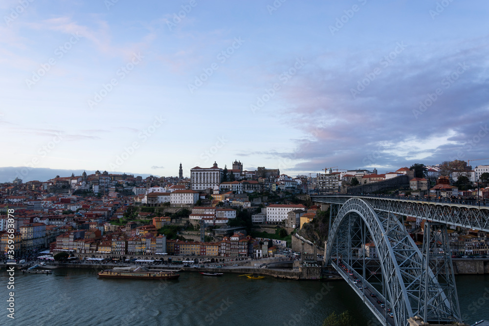 Porto view, with Dom Luís Bridge and Douro river. Sunset, blue sky and clouds. Boats on the river