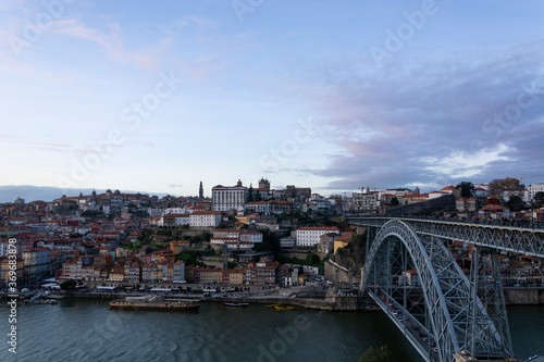 Porto view, with Dom Luís Bridge and Douro river. Sunset, blue sky and clouds. Boats on the river