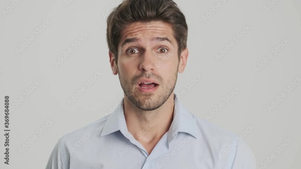 A close-up view of a shocked young man is looking to the camera isolated over white background A close-up view of a shocked young man is looking to the camera isolated over white background
