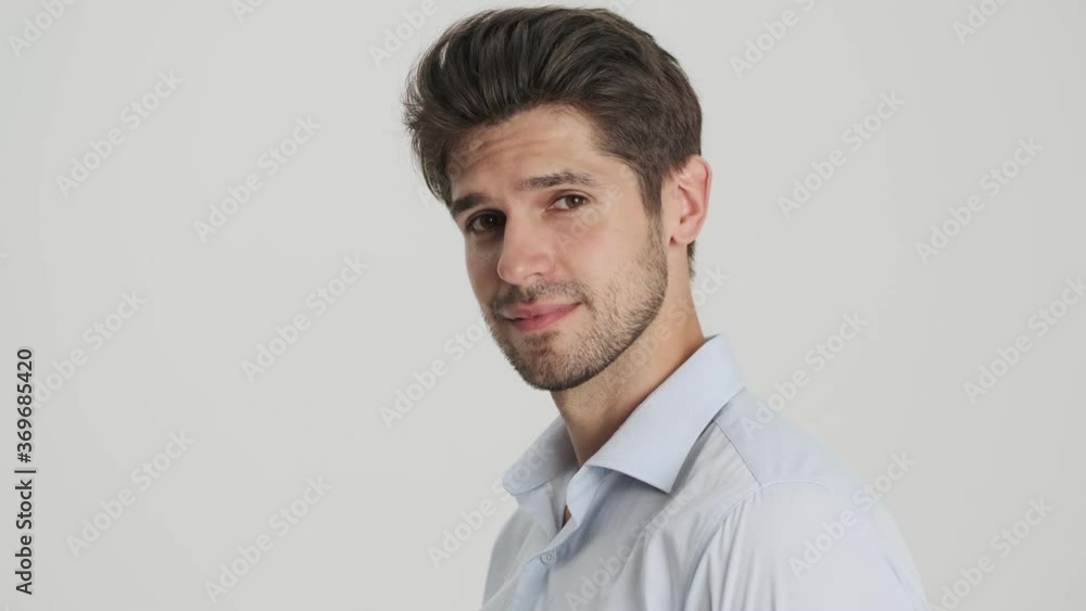 A close-up view of a happy young man is posing to the camera standing isolated over white background A close-up view of a happy young man is posing to the camera standing isolated over white background
