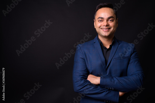 Portrait of happy young handsome Indian businessman in suit