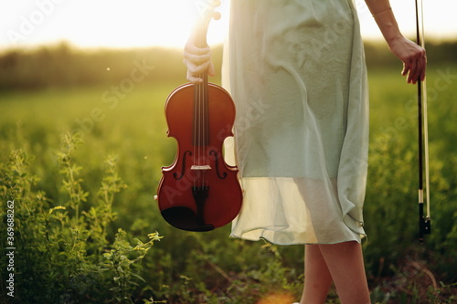 Violin in the hands of a young female violinist in the sunset light. photo