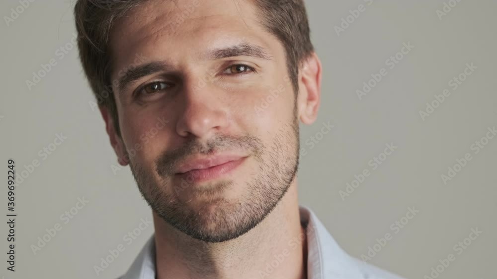 A close-up view of a handsome young man is posing to the camera standing isolated over white background A close-up view of a handsome young man is posing to the camera standing isolated over white background