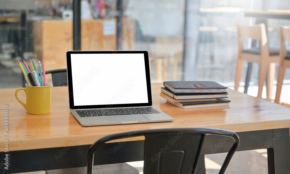 A laptop and notebook with stationery are placed on the table in the comfortable workspace. A laptop and notebook with stationery are placed on the table in the comfortable workspace.