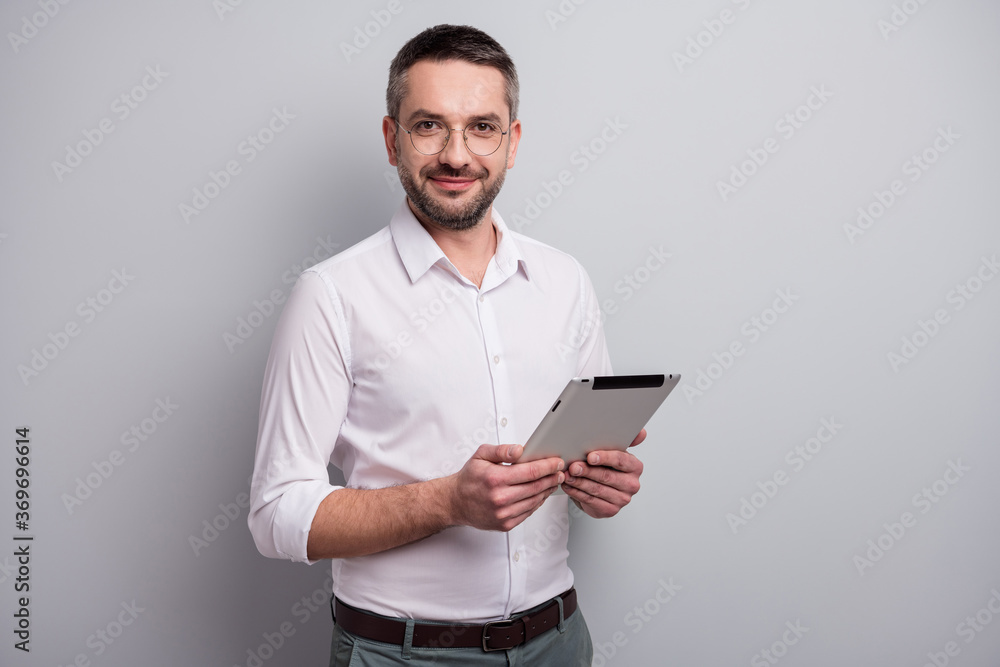 Portrait of his he nice attractive intellectual content mature man holding in hands ebook analyzing review report isolated over light gray pastel color background Portrait of his he nice attractive intellectual content mature man holding in hands ebook analyzing review report isolated over light gray pastel color background