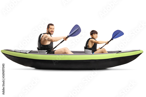 Young man and a boy with safety vests sitting in a kayak with paddles