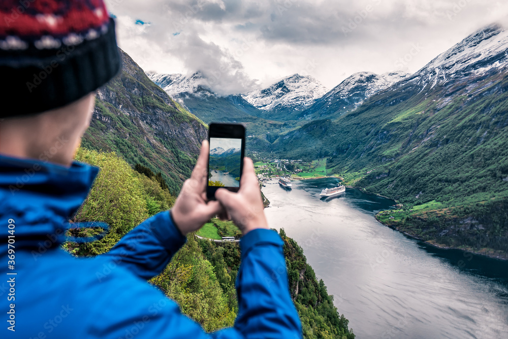 tourist takes photo of Geiranger fjord on smartphone - obrazy, fototapety, plakaty 