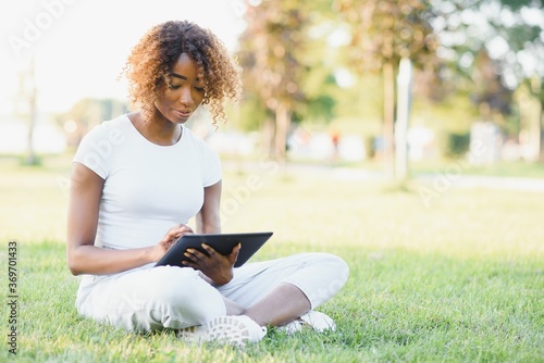 Outdoor portrait of a smiling teenage black girl using a tactile tablet - African people
