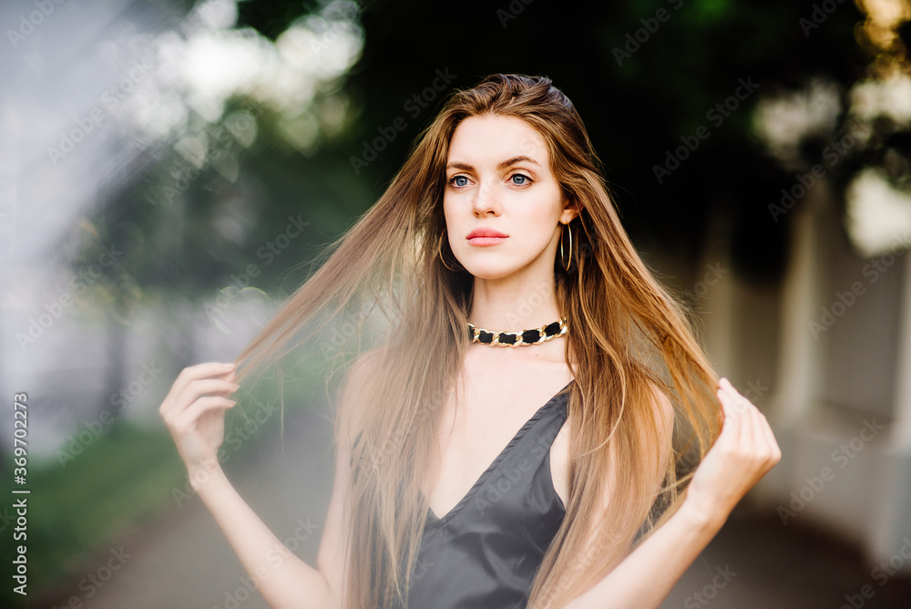 Naklejka premium portrait of beautiful young girl in black dress outdoors, attractive woman with long hair