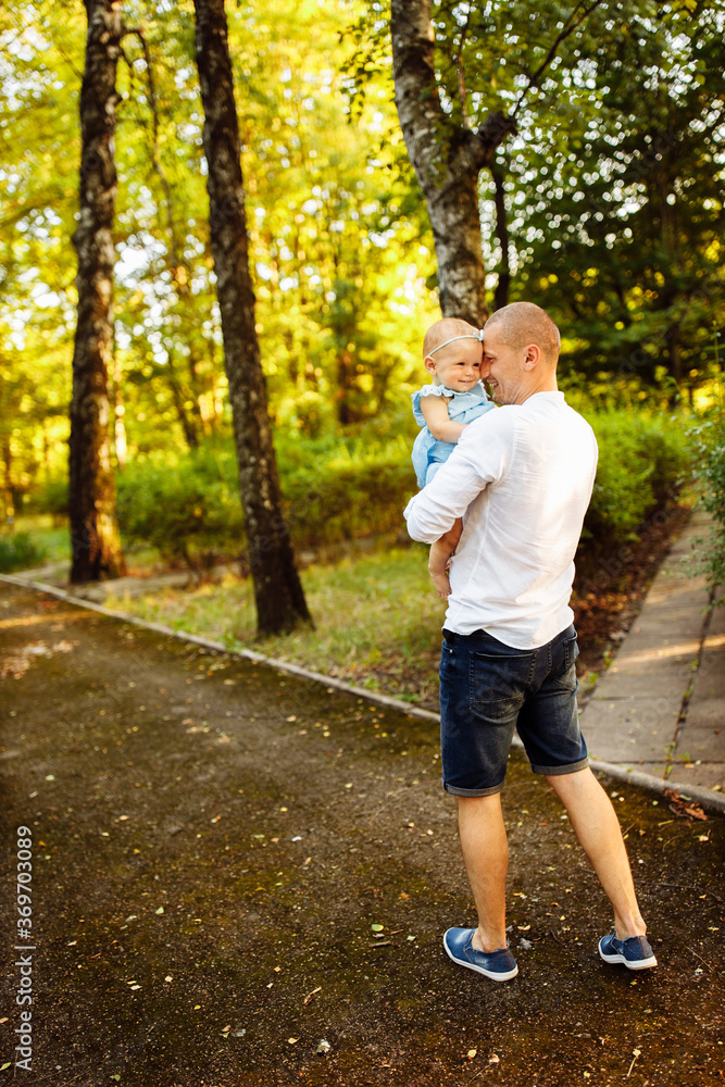 Caring father with little daughter walking at the park, handsome man hold in arms lovely baby girl, dad looking at smiling toddler, enjoy tender family moments, weekend outdoors, childhood concept Caring father with little daughter walking at the park, handsome man hold in arms lovely baby girl, dad looking at smiling toddler, enjoy tender family moments, weekend outdoors, childhood concept