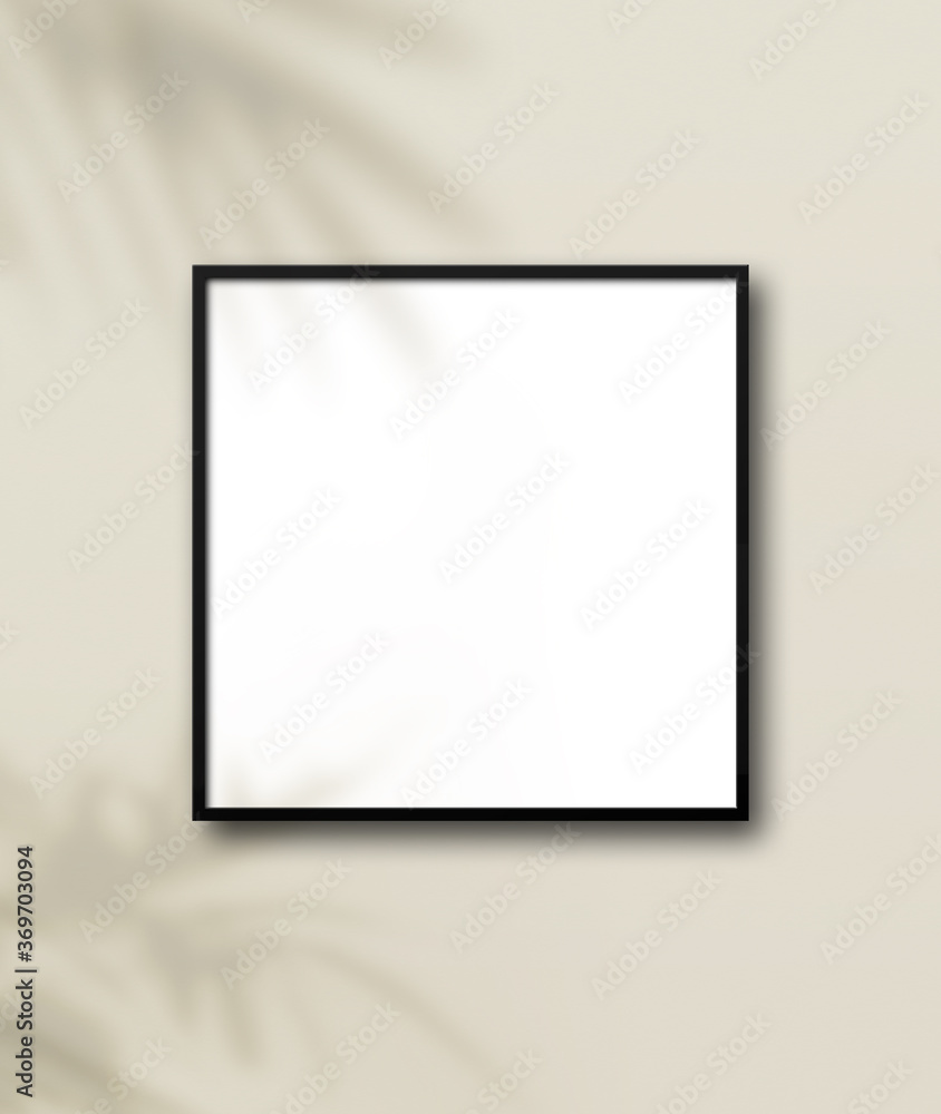 Black square picture frame hanging on a light beige wall Black square picture frame hanging on a light beige wall
