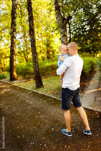 Caring father with little daughter walking at the park, handsome man hold in arms lovely baby girl, dad looking at smiling toddler, enjoy tender family moments, weekend outdoors, childhood concept