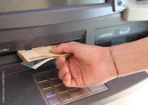 person withdraws money in European banknotes from an ATM