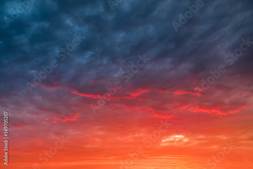 Colorful and dramatic sunset with red tinted clouds. Sky Background or texture