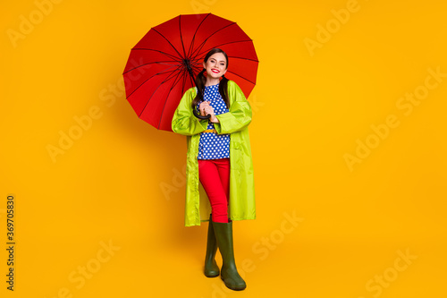 Full length body size view of her she nice attractive cheerful cheery glad fashionable girl wearing green raincoat open parasol isolated bright vivid shine vibrant yellow color background