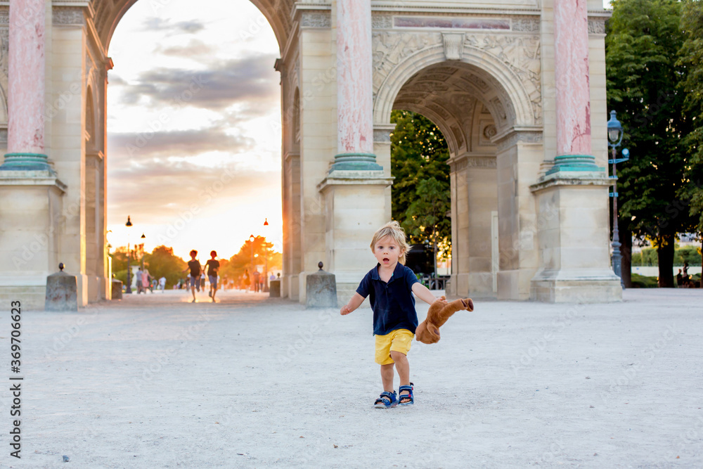 Cute toddler boy, playing with teddy bear, visiting Paris during the summer