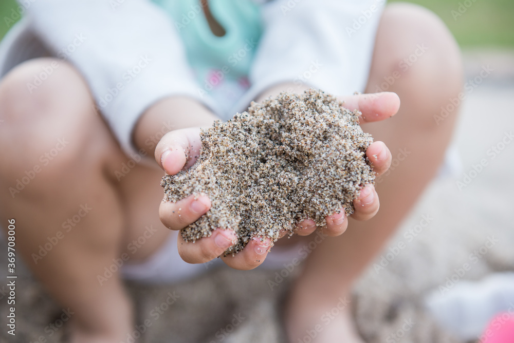 Close up hand of little girl playing on the sand