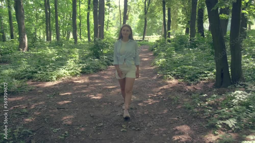 Beautiful young girl walks in the park in summer. Sunny bright day. 4k Beautiful young girl walks in the park in summer. Sunny bright day. 4k
