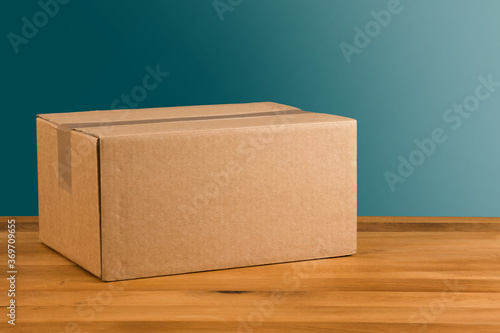 Photos ungeöffnetes Paket auf Holztisch vor blauem Hintergrund