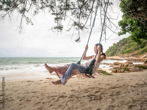 Vacation concept. Asian woman playing swing on the beach in Samed, Thailand.