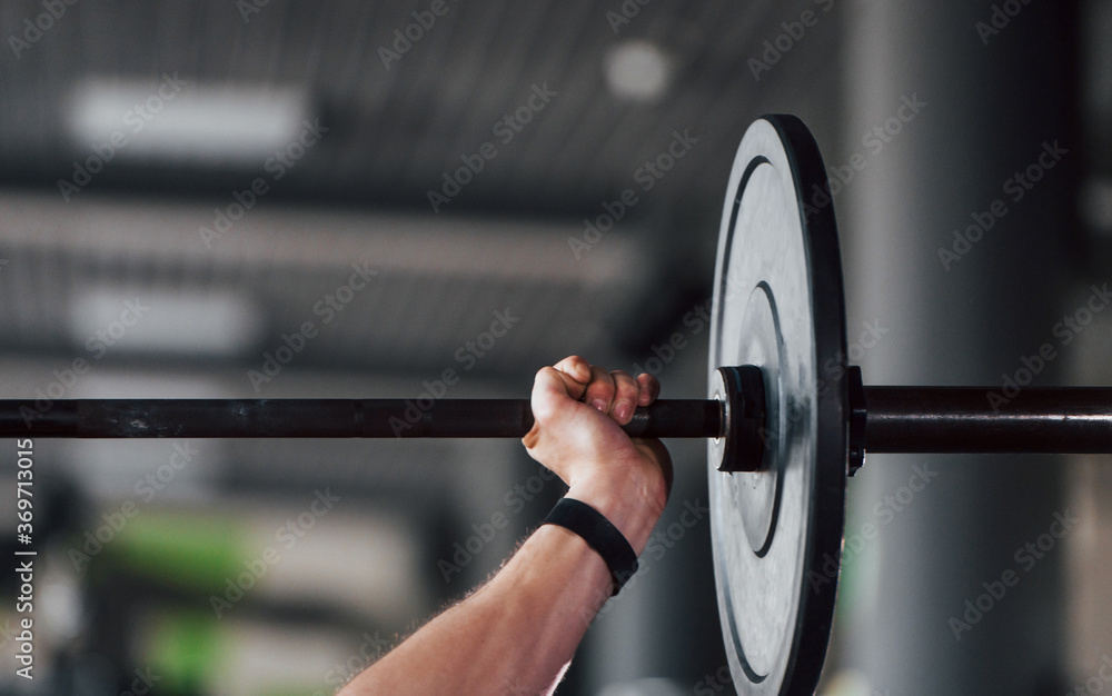 Lifting barbell. Young sportive strong man in black wear have workout day in gym Lifting barbell. Young sportive strong man in black wear have workout day in gym