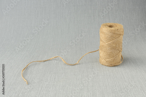 Spool of an economic rope (twine) for packing close-up on grey background. copy space. handmade, needlework, craft, building, construction and eco concept