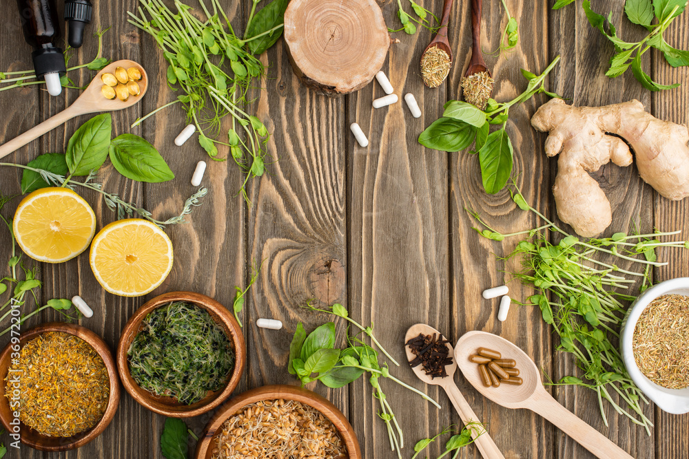 top view of pills and green herbs on wooden surface, naturopathy concept top view of pills and green herbs on wooden surface, naturopathy concept