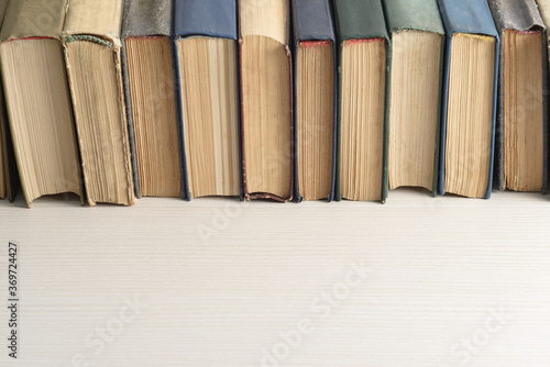 A row of old  faded  multicolored  yellowed books on a light background. Minimal style  copy space  side view