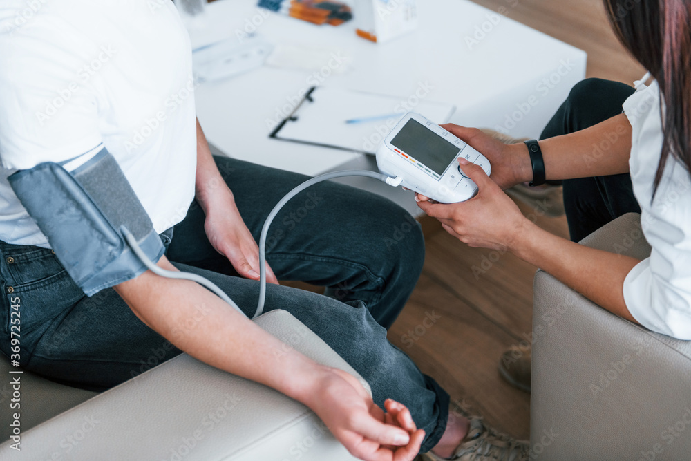 Obraz premium Measuring blood pressure. Young woman have a visit with female doctor in modern clinic