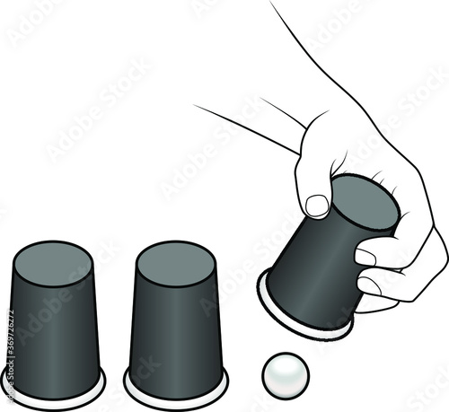 A hand lifting a cup of a cups-and-ball game.