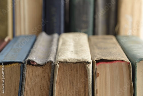 A row of old, faded, multicolored, yellowed books on a light background. Minimal style, copy space, side view